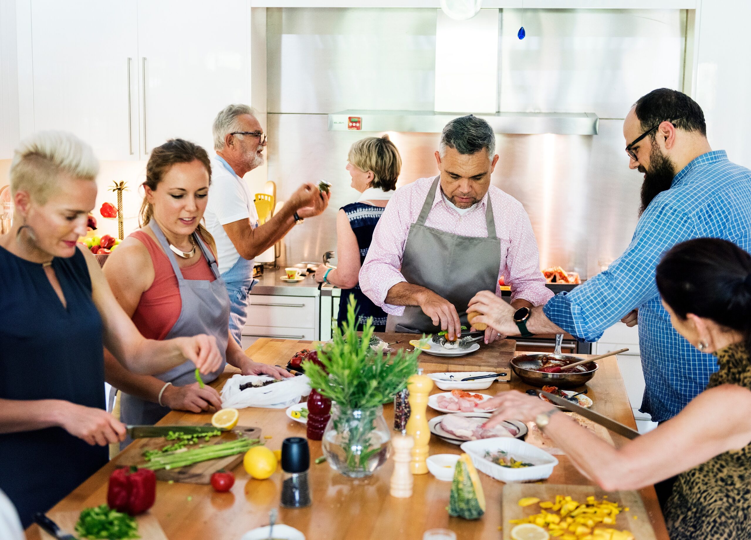 Menschen stehen an einem Küchentisch und bereiten Zutaten zum Kochen zu.